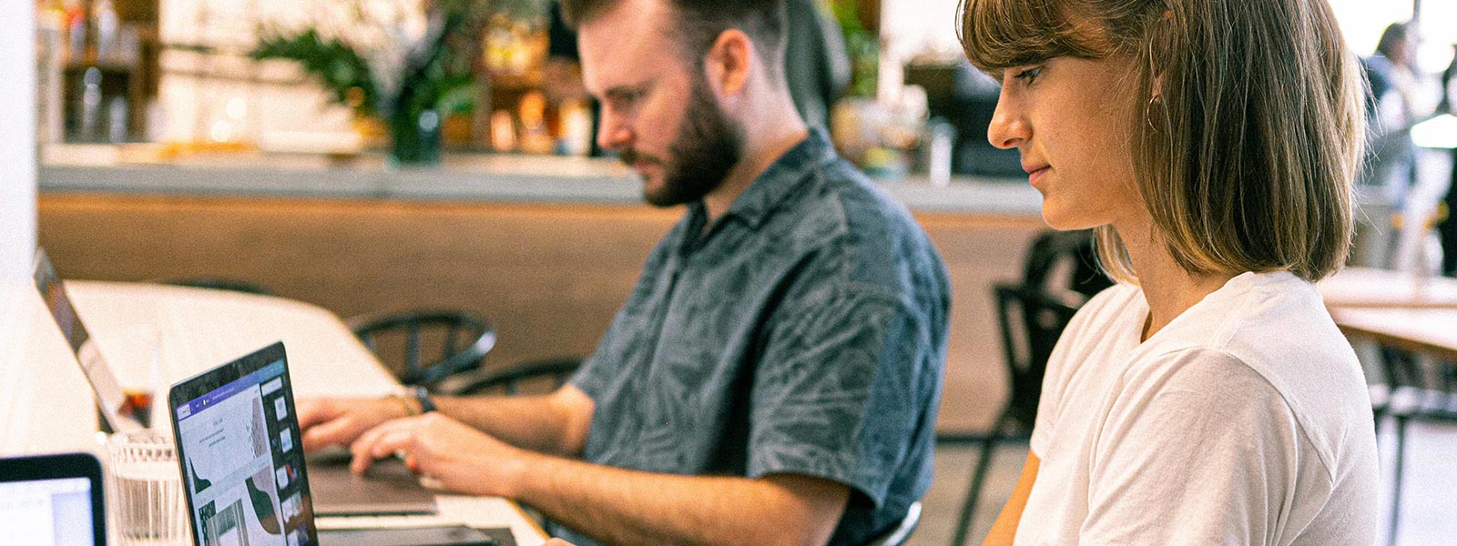 A man and a woman individually working on laptops