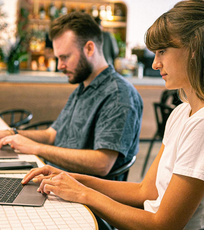 A man and a woman individually working on laptops