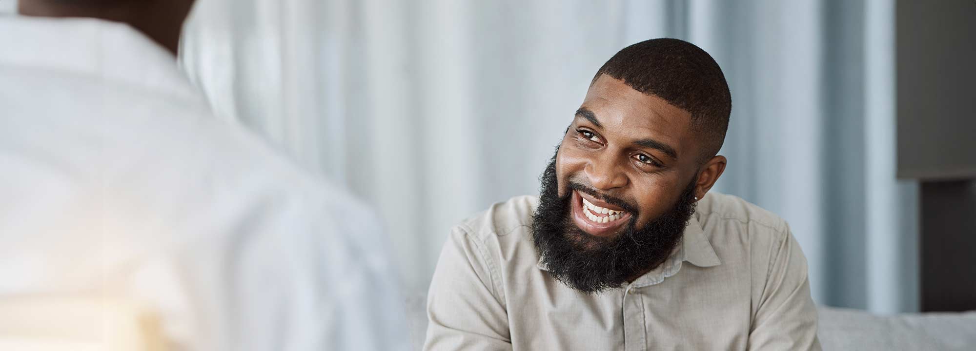 A happy man smiling at an unknown person in the foreground